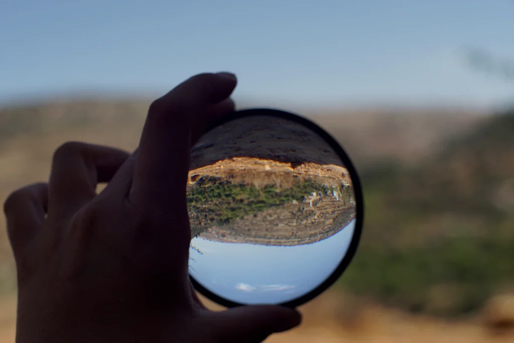 thesun still firstimage hand holding a magnifying glass showing a landscape upside down